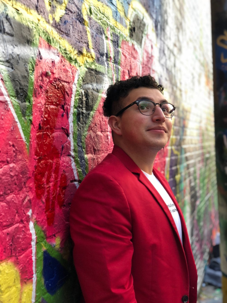 Carlos Garcia Leon stands in front of a colorful mural.